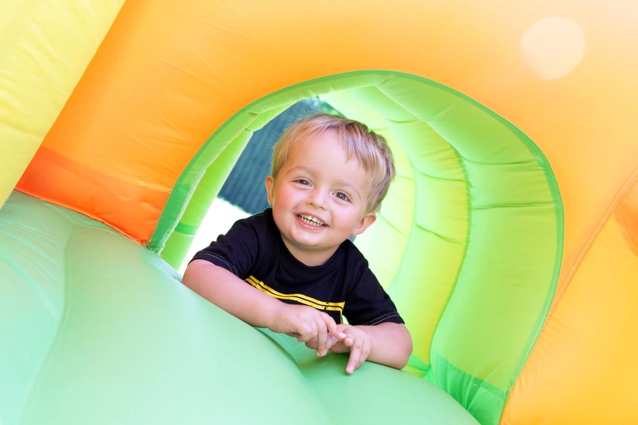 A little boy is smiling in an inflatable castle.