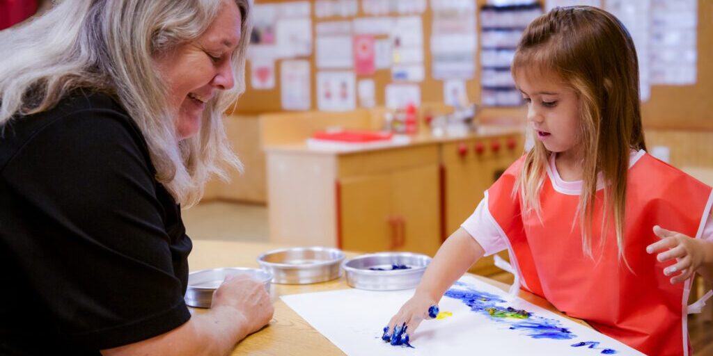 A Teacher from Gingerbread Preschool doing arts and crafts with a child.